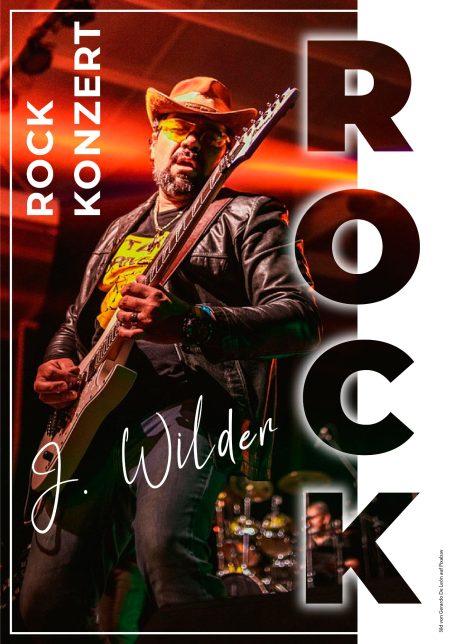 Mann spielt Gitarre auf der Bühne bei einem Rockkonzert, mit dramatischer Beleuchtung.