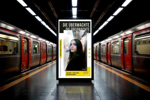 Frau mit nachdenklichem Ausdruck vor einem Werbeschild in einer U-Bahn-Station.